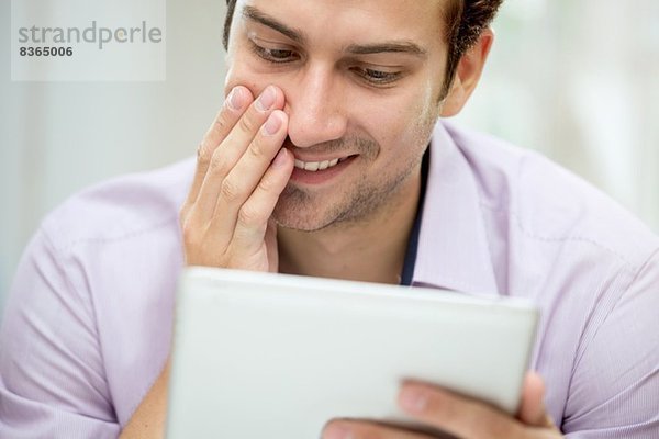 Junger Mann betrachtet Nachricht auf digitalem Tablett