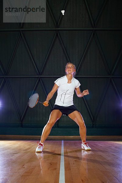 Junge Frau spielt Badminton auf dem Platz