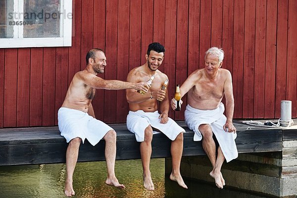 Drei Männer bei einem Bier vor der Sauna