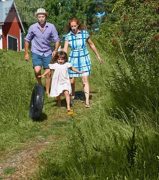 Eltern und Mädchen rollender Reifen auf dem Weg  Utvalnas  Gavle  Schweden