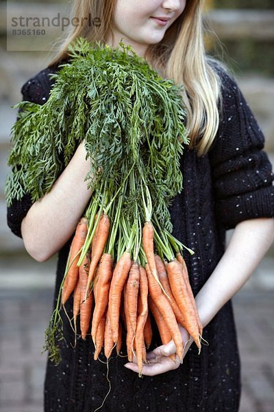 Nahaufnahme eines Mädchens mit einem Haufen Karotten
