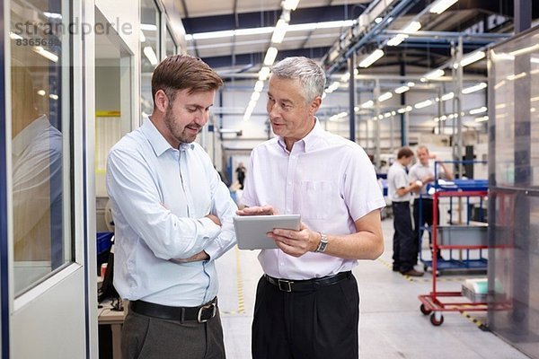 Manager und Mitarbeiter bei der Suche nach digitalen Tabletts in der Maschinenfabrik