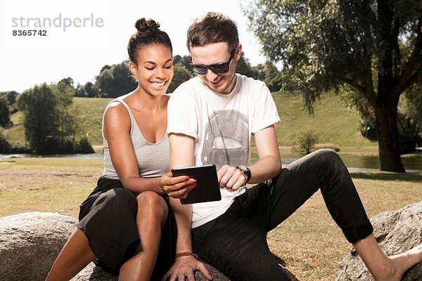 Junges Paar mit digitalem Tablett im Park