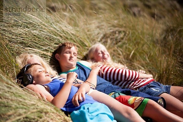 Vier Freunde beim Entspannen in den Dünen  Wales  UK