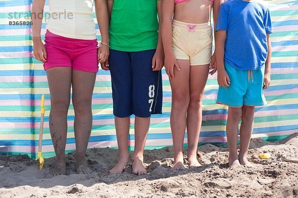 Vier Freunde stehen am Strand und tragen Shorts  Wales  UK