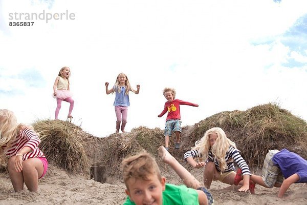 Gruppe von Kindern  die von Sanddünen springen  Wales  UK