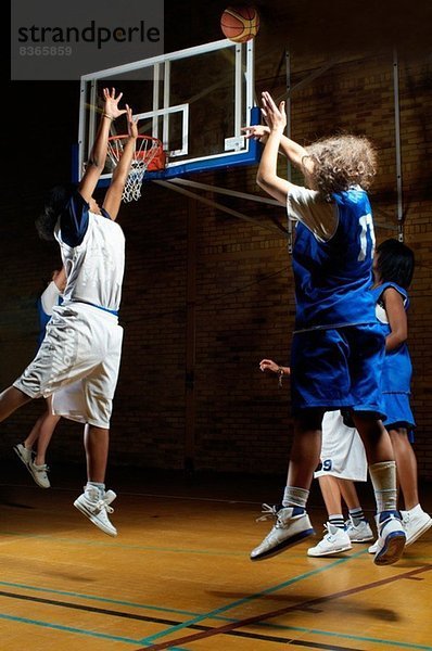 Basketballspieler springen für Ball