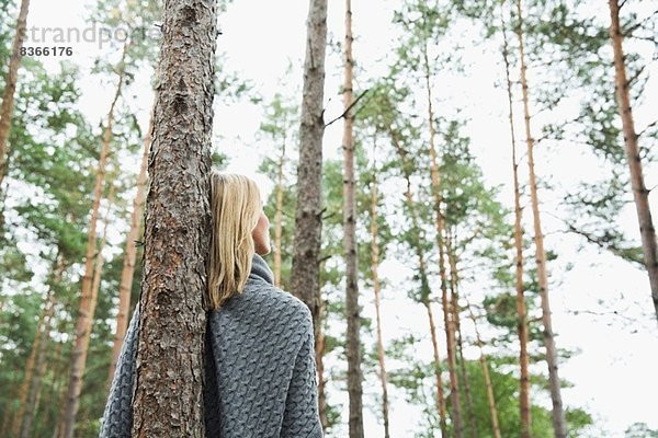 Mittlere erwachsene Frau am Baum lehnend  niedriger Winkel