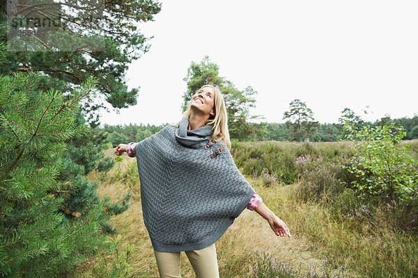 Mittlere erwachsene Frau mit grauem Poncho  die nach oben schaut.