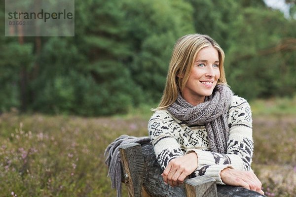 Mittlere erwachsene Frau mit Pullover auf der Bank