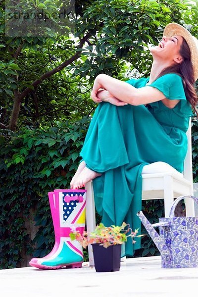 Junge Frau im grünen Kleid sitzend auf dem Stuhl lachend