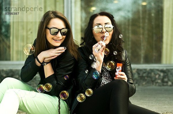 Zwei junge Frauen  die Spaß haben  Blasen zu blasen.