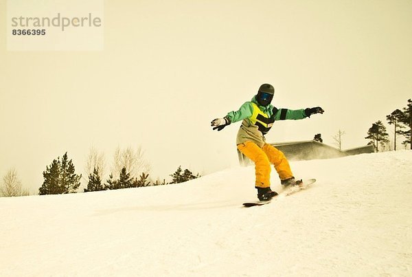 Junger Mann beim Snowboarden auf dem Berg