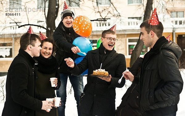 Gruppe junger Freunde auf der Stadtstraße mit Geburtstagskuchen