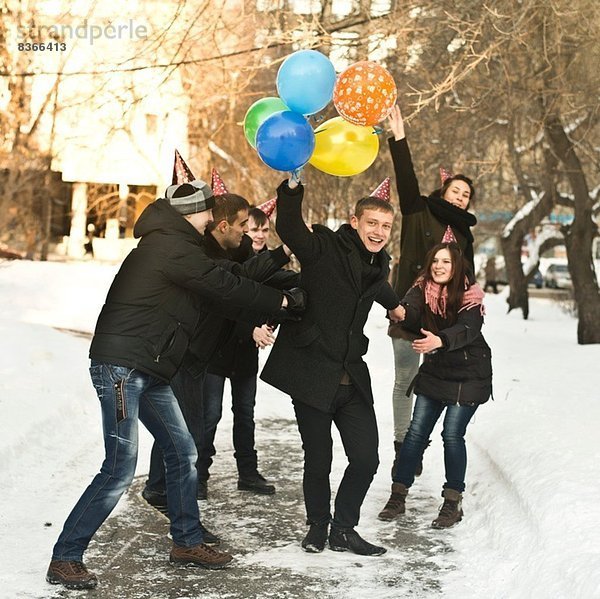 Gruppe junger Freunde mit Partyhüten und Ballons