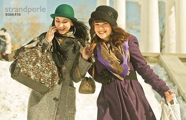 Zwei junge Frauen tragen Taschen im Schnee