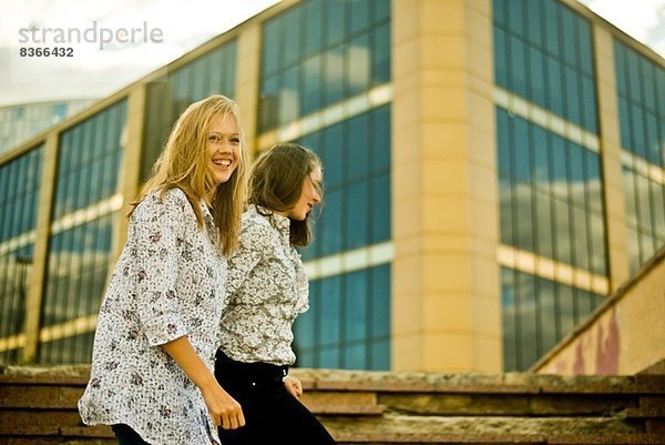 Zwei junge Frauen  die vor dem Bürogebäude laufen.