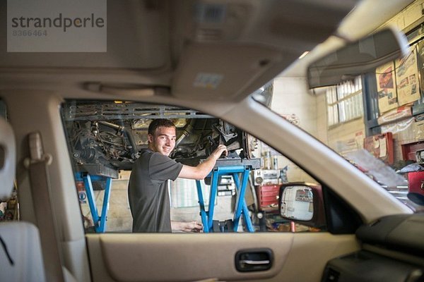 Mechaniker lächelt durch die Autoscheibe auf die Kamera zu
