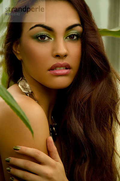 Porträt einer jungen Frau mit grünem Lidschatten und Nagellack