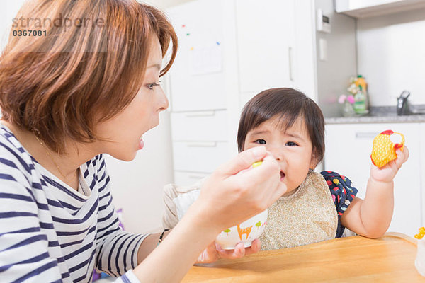 Mutter füttert Baby in der Küche