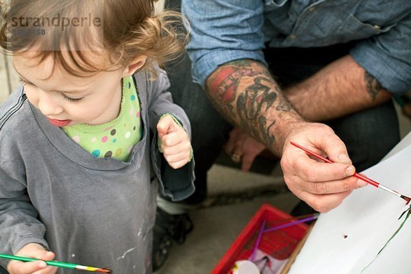 Vater und Töchter malen auf Staffelei