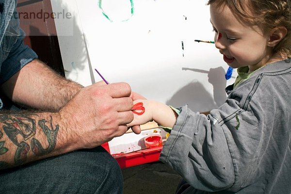 Vater malt Herzform auf Tochterhand