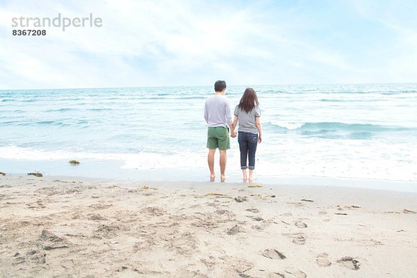 Junges Paar hält Hände am Strand