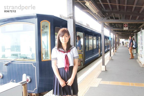 Frau in Schuluniform auf dem Bahnsteig am Bahnhof