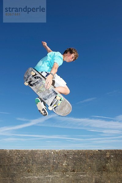 Teenager Junge in der Luft auf dem Skateboard