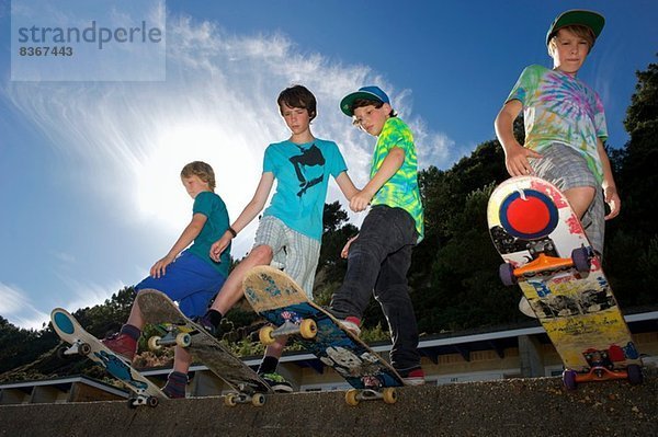 Porträt von vier Jungen auf Skateboards