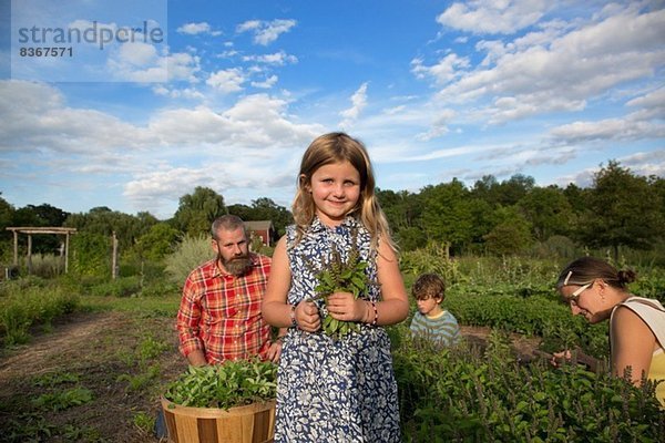 Porträt eines Mädchens  das einen Haufen Blätter auf einer Familien-Kräuterfarm hält