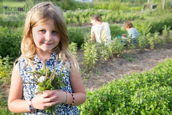 Porträt eines Mädchens mit Laubbüscheln auf einer Kräuterfarm