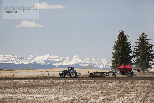 Berg  bedecken  Wolke  Himmel  Traktor  Nutzpflanze  Feld  blau  Sämaschine  Alberta  Kanada  anpflanzen  Schnee
