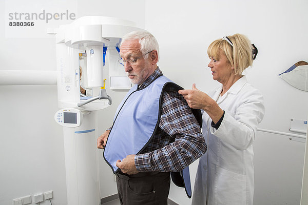 Mann wird fürs Röntgen des Gebisses vorbereitet  mit Bleiweste als Strahlungsschutz  Deutschland