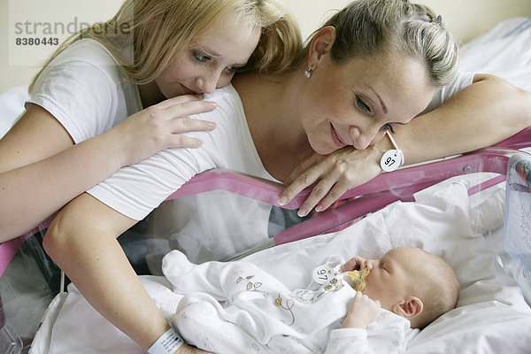 Mutter im Krankenhaus mit ihrer älteren Tochter und einem neugeborenen Baby