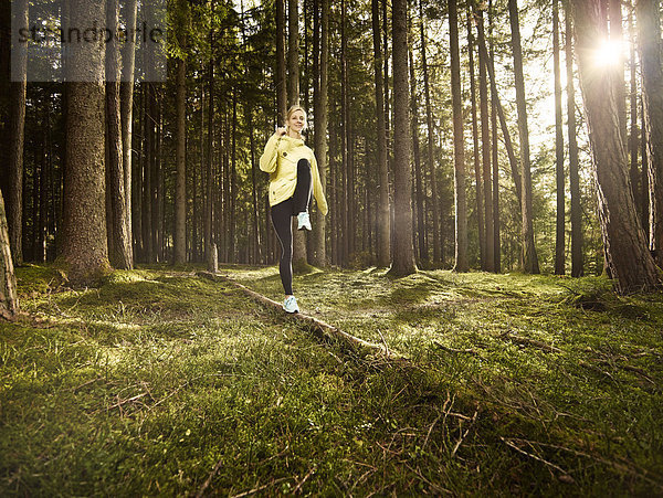 Frau macht eine Fitnessübung auf einem umgefallenen Baumstamm im Wald  Tirol  Austria