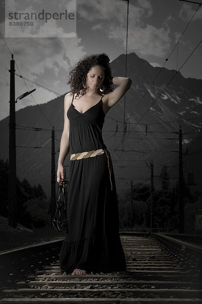 Frau im Kleid geht auf einem Bahngleis  Tirol  Austria