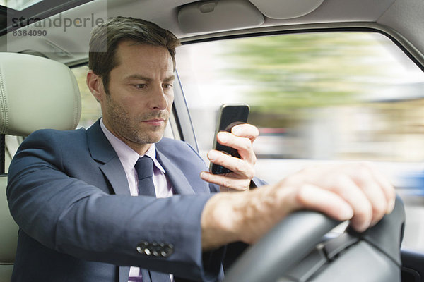 Geschäftsmann beim Blick auf Smartphone im Auto