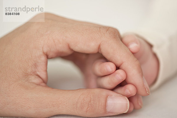 Baby und Mutter halten sich an den Händen  abgeschnitten  Nahaufnahme