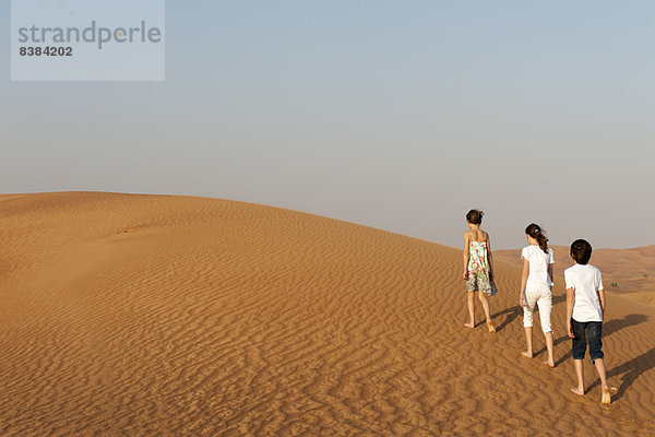 Kinder wandern in der Wüste  Rückansicht