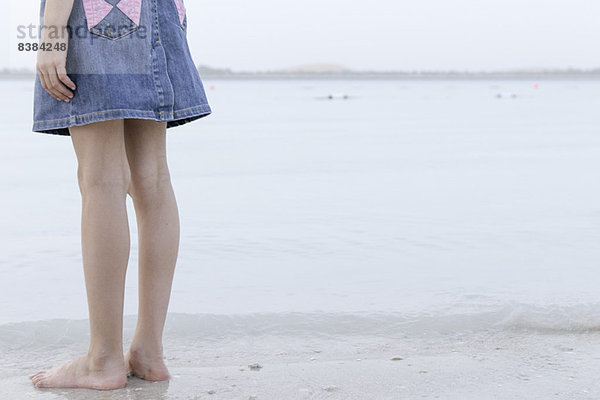 Mädchen am Rande des Wassers am Strand stehend  niedriger Abschnitt