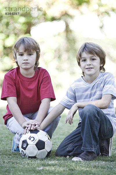 Jungen hocken auf dem Spielfeld mit Fußball  Portrait