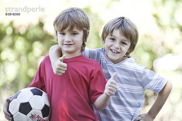 Jungen mit Fußball  Daumen hochhaltend  Portrait