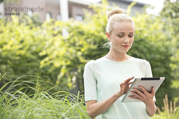 Junge Frau mit digitalem Tablett im Freien