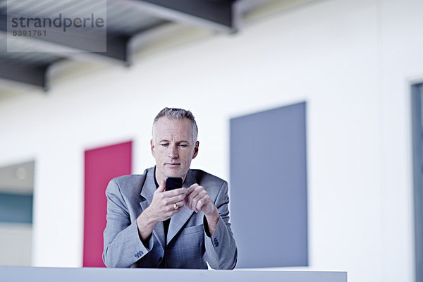 Geschäftsmann mit Handy in der Lobby