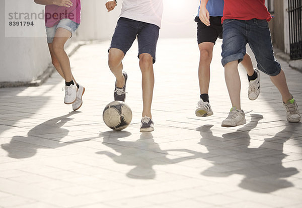 Kinder spielen mit Fußball in der Gasse