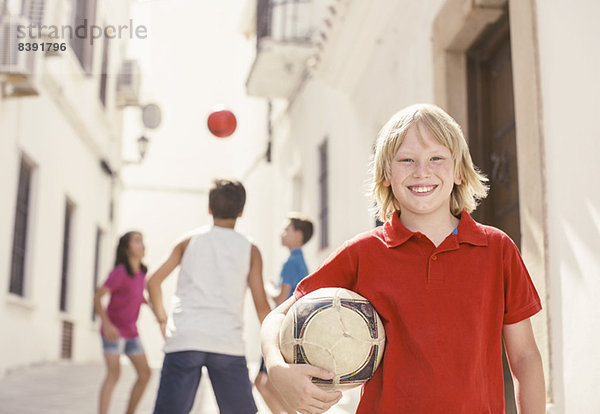 Junge hält Fußball in der Gasse