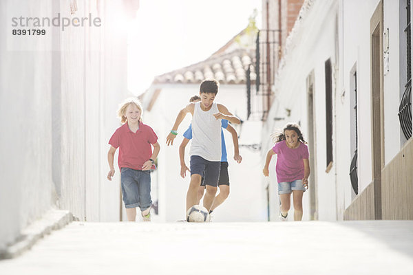 Kinder spielen Fußball in der Gasse