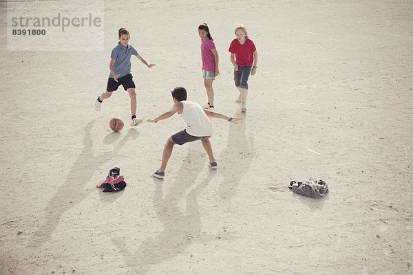 Kinder spielen mit Fußball im Sand