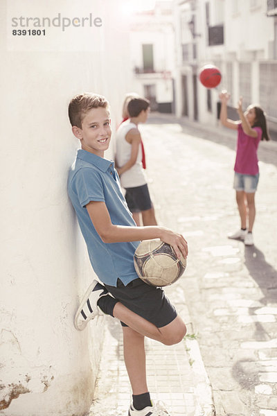 Junge hält Fußball in der Gasse